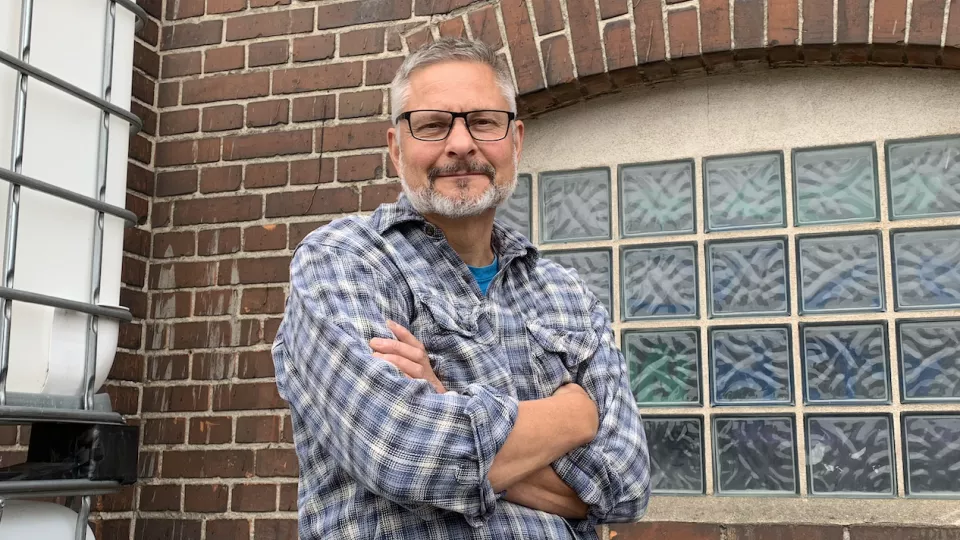 Portrait photo of a man in front of a brick building.