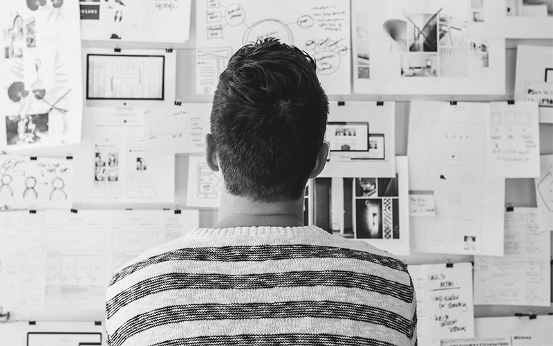 Person in front of a notice board. Photo.