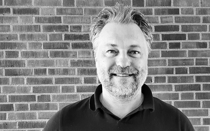 Photo portrait of a man in front of a brick wall.