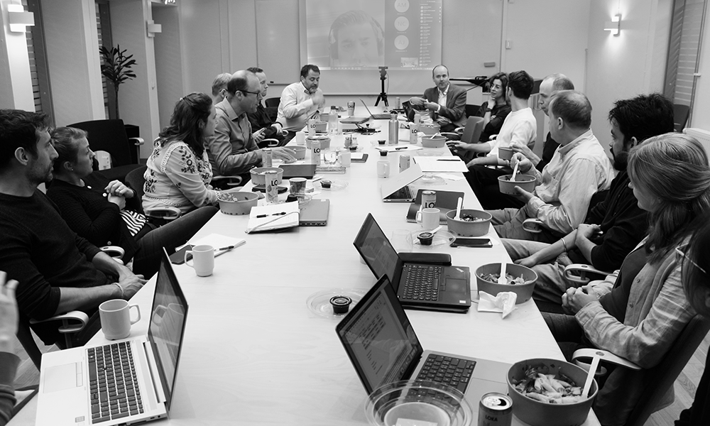 People by a table in a meeting room. Photo.