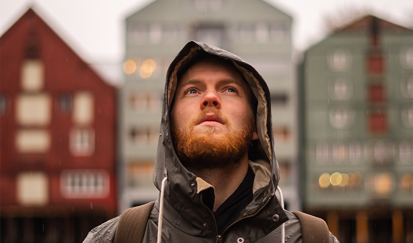 A man in outdoor clothes in front of buildings. Photo.