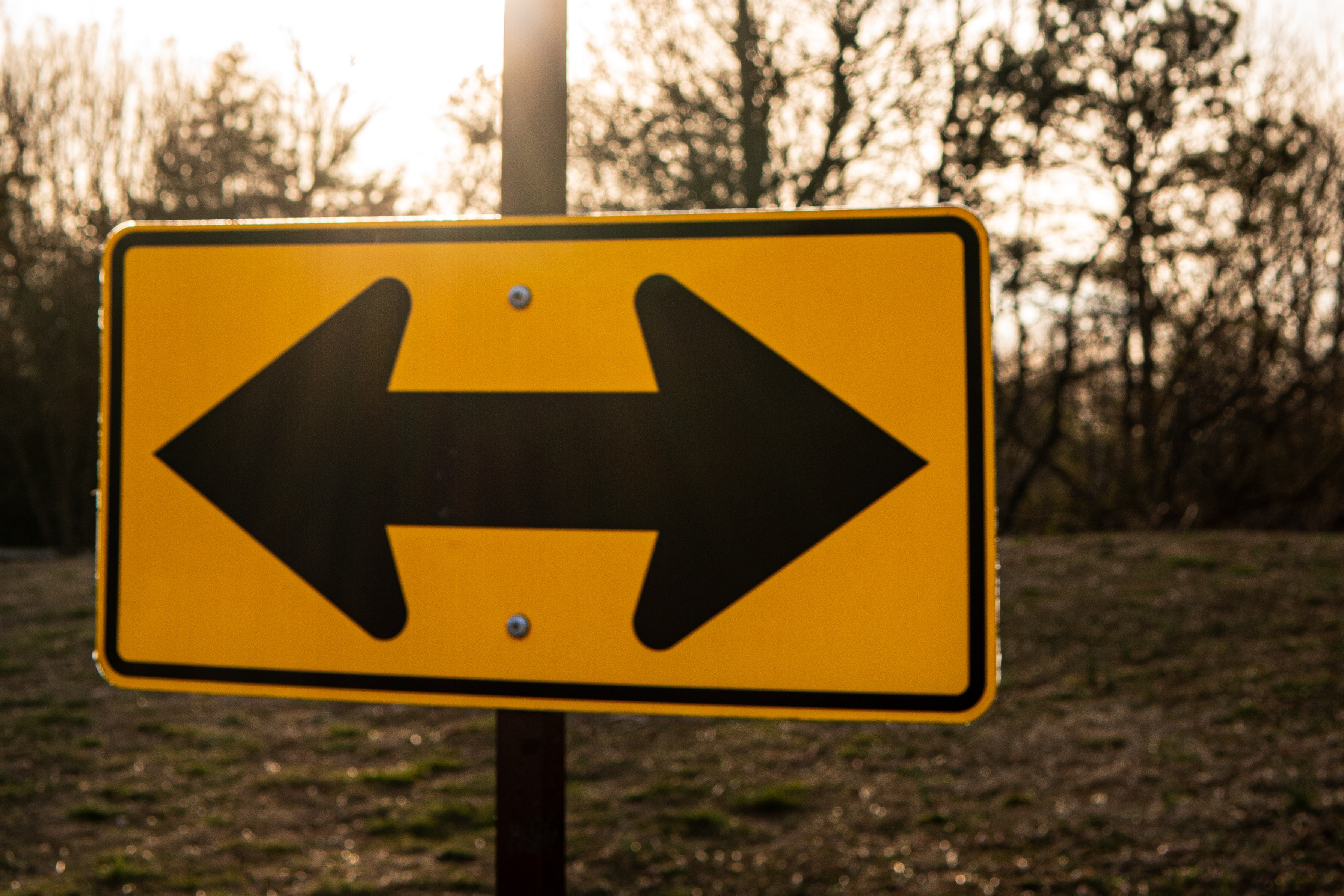 Photo of a roadsign with arrows pointing in opposite directions.