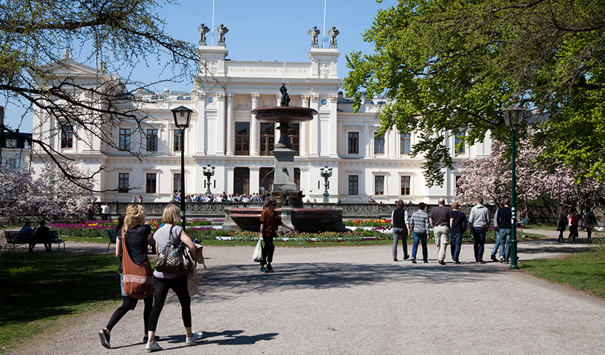 Photo of people walking by a large white building.