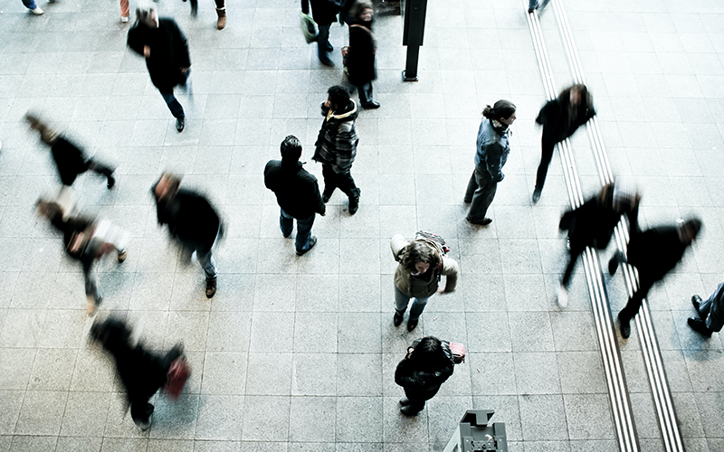 Photo of people seen from above walking across a tiled floor.