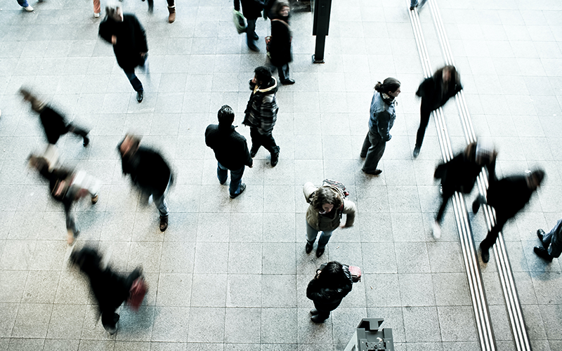 People walking across a paved floor, seen from above.