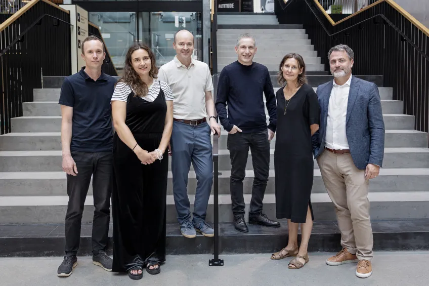 Six people standing in a line facing the camera. Photo.